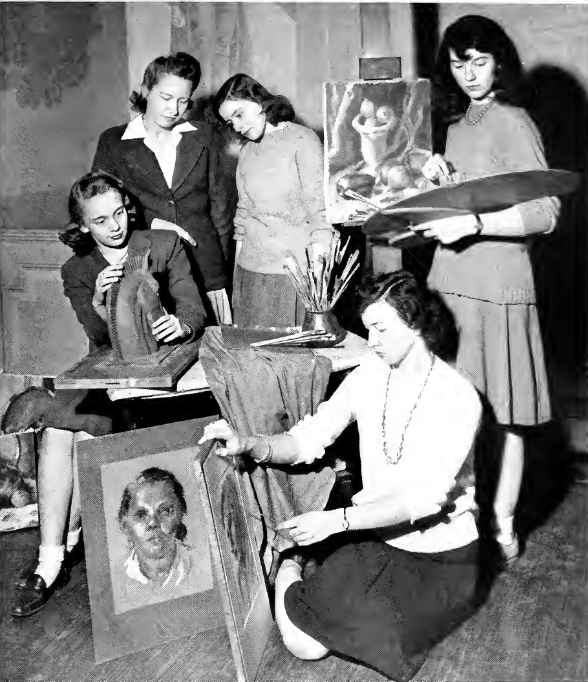 A black and white photo of five woman in the Art Club. One is holding an essal, one is painting while kneeling on the floor, two is working on making a horse head. Two women are in the background looking at the horse head.